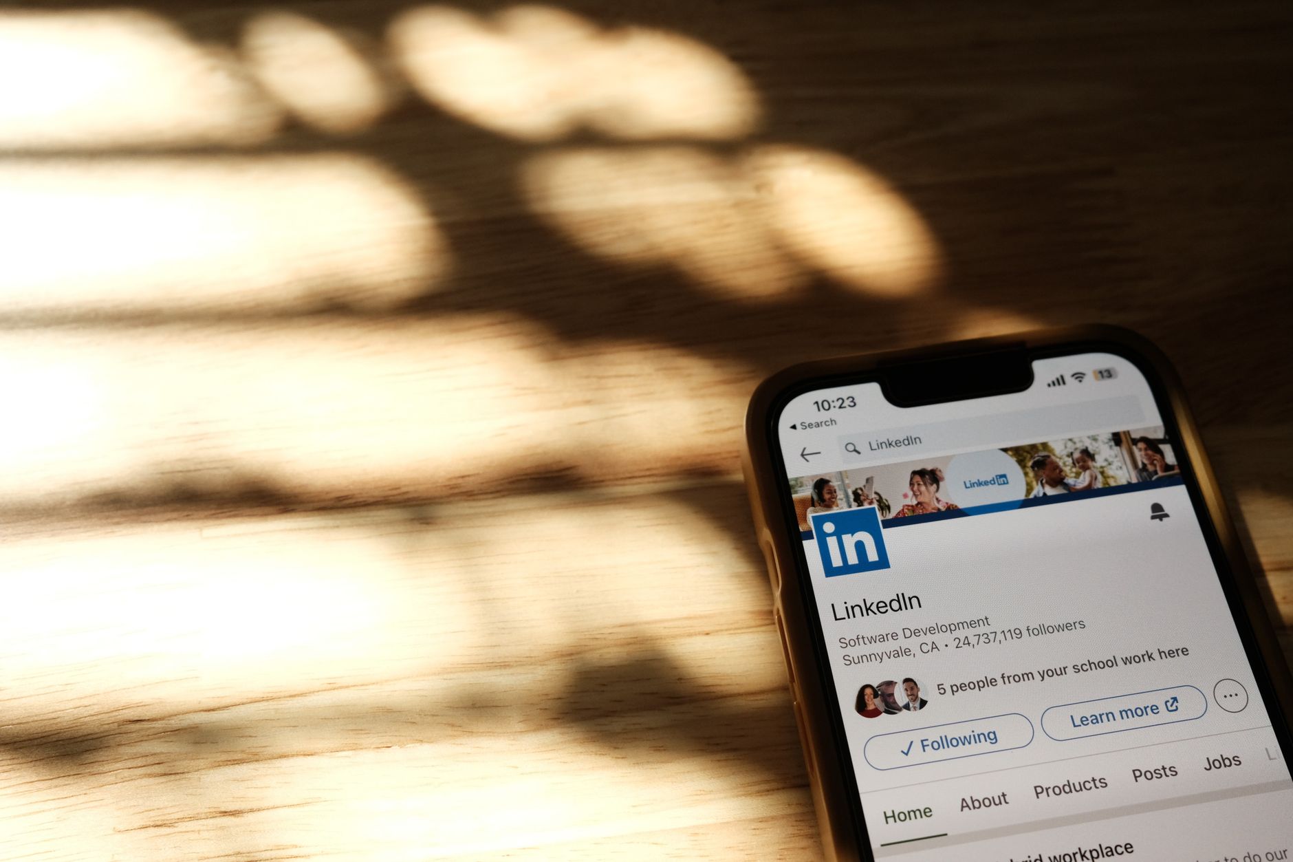 Smartphone mit geöffnetem LinkedIn-Profil auf einem Holztisch für Werbung auf LinkedIn