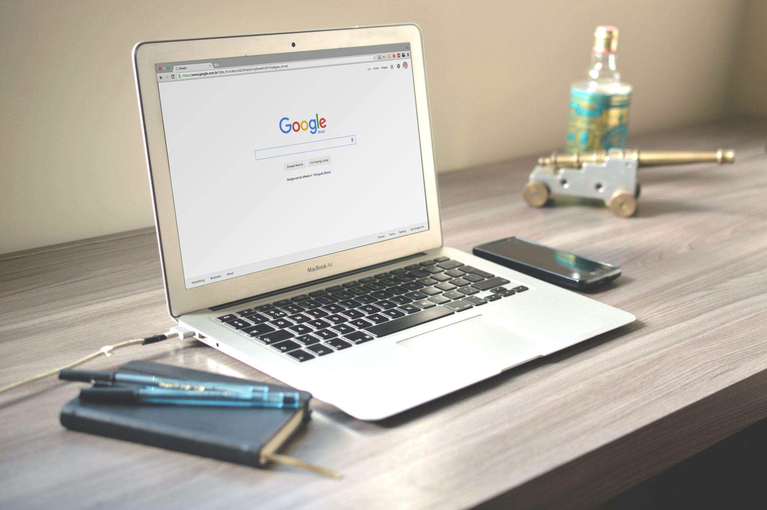 Arbeitsplatz mit Laptop, auf dem die Google-Suche geöffnet ist, daneben Smartphone und Notizbuch